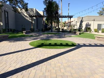 a circle of grass in the middle of a brick sidewalk